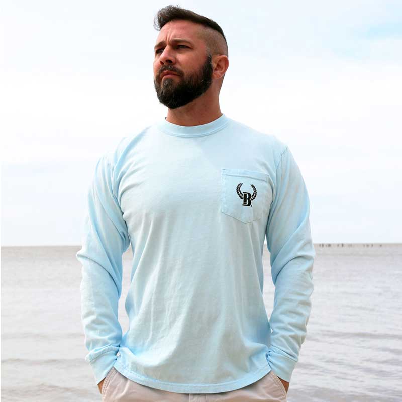 A man standing on the beach wearing a light blue shirt.