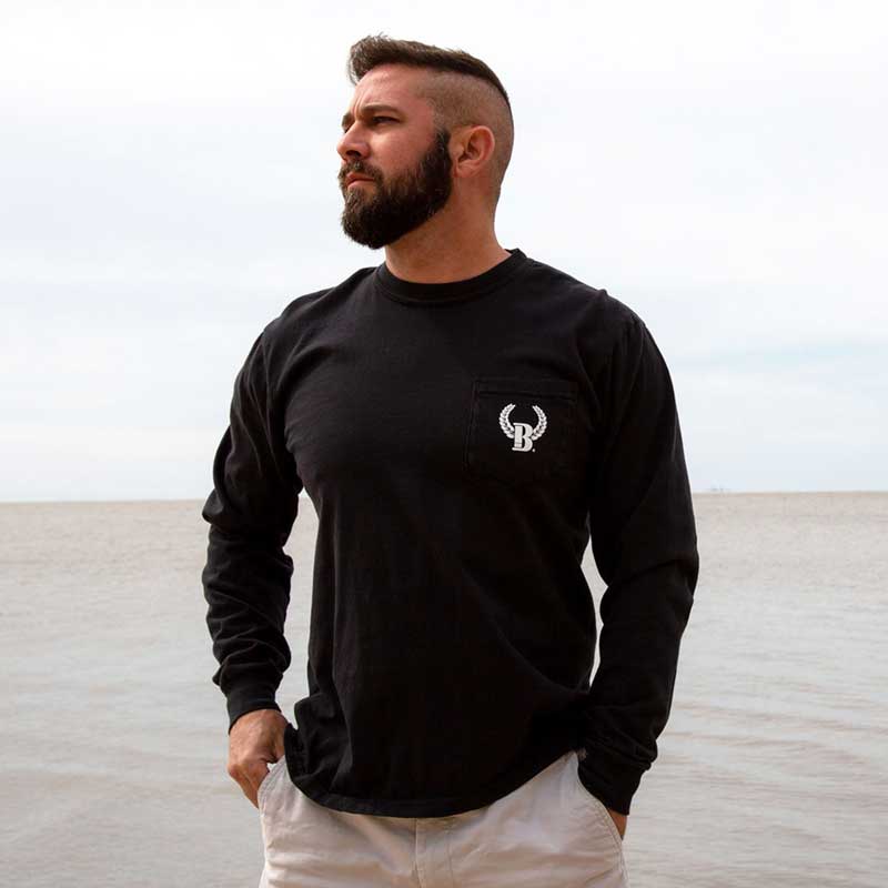 A man standing in front of the ocean wearing a black long sleeve shirt.