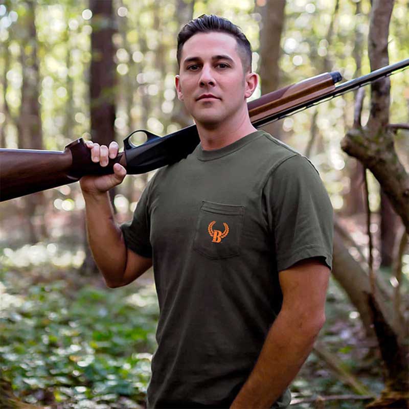 A man holding a rifle in the woods.