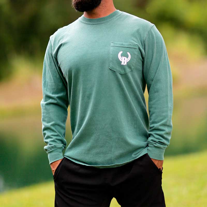 A man standing in the grass wearing a long sleeve shirt.