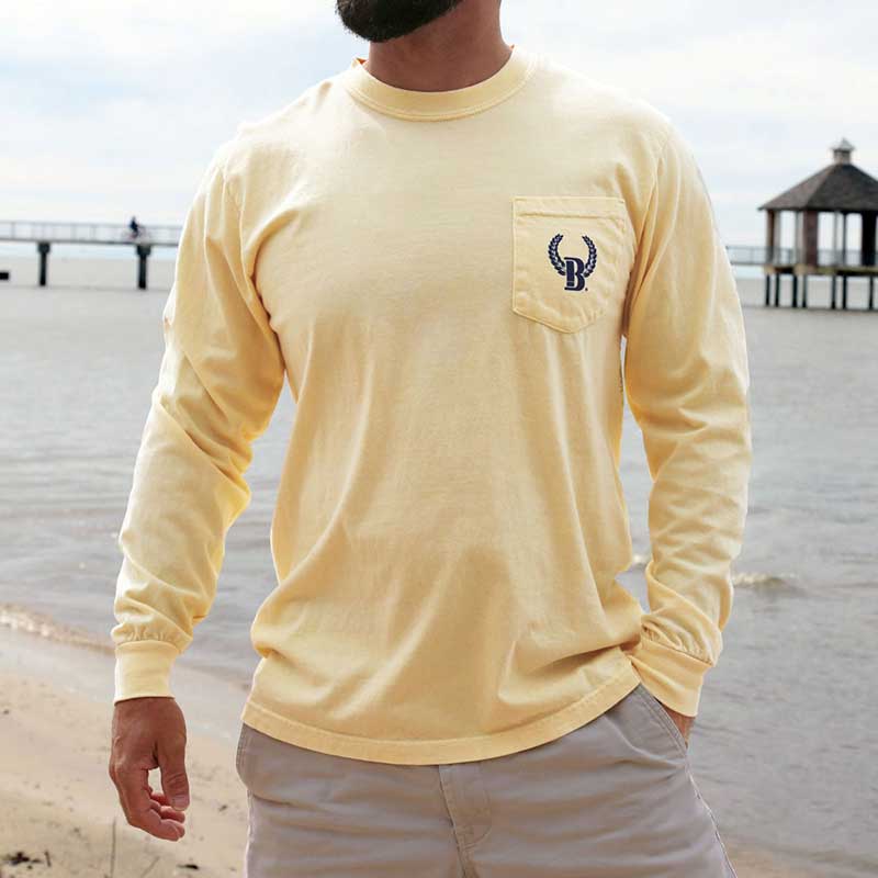 A man standing on the beach wearing a long sleeve shirt.