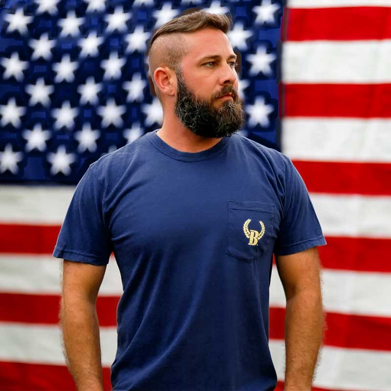 A man with a beard and mustache standing in front of an american flag.