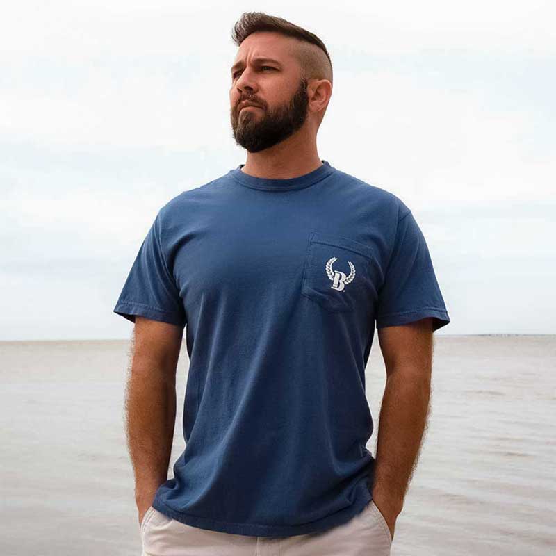 A man standing on the beach wearing a blue shirt