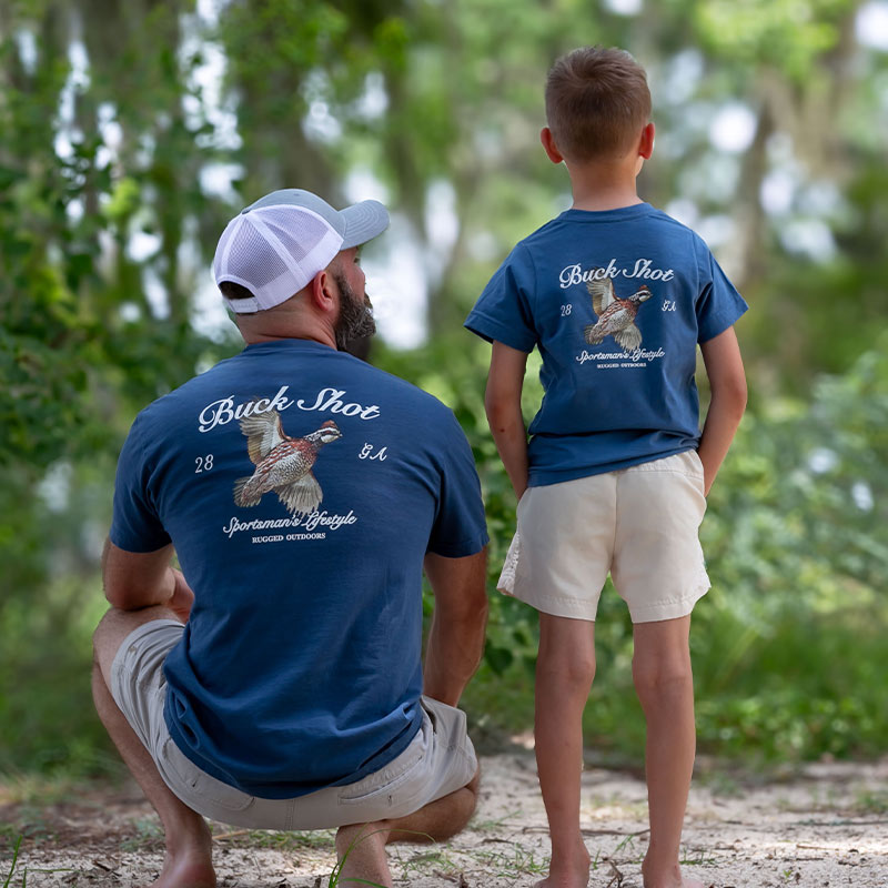 Quail father and son back Father and youth wearing matching t-shirts featuring a Bobwhite Quail graphic, father looking towards son