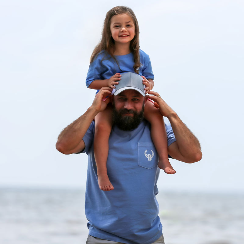 Daddy and me matching God Guns and Girt front view Little girl on Dad's shoulders wearing matching t-shirts